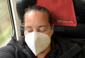 Berlin  Deutschland  Frau mit FFP2-Maske schlaeft waehrend einer Zugfahrt