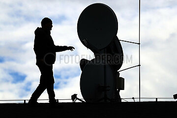 Dresden  Deutschland  Silhouette: Mann steht vor Satellitenschuesseln auf einem Dach
