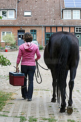 Amelinghausen  Frau fuehrt ihr Pferd zum Putzplatz