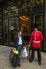 CHINA. MACAU. A Chinese tourist walks ahead a British guard outside the hotel Grand Emperor
