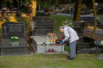 Polen  Warschau - Angehoerige bei der Grabpflege auf dem Powazki Militaerfriedhof (Cmentarz Wojskowy)