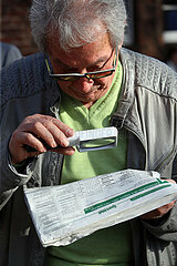 Hoppegarten  Deutschland  Mann liest eine Zeitung mit einer Lupe
