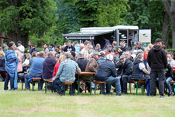 Graditz  Deutschland  Menschen sitzen bei einer Veranstaltung auf Baenken an Tischen