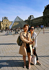 FRANCE. PARIS (75) CHINESE TOURISTS TAKING PHOTOS ON THE ESPLANADE OF THE LOUVRE MUSEUM  WITH THE PYRAMID IN THE BACKGROUND