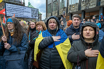 Deutschland  Bremen - Jahrestag des russischen Angriffkriegs gegen die Ukraine  ukrainische Teilnehmer der Demonstration WE STAND WITH UKRAINE singen ihre Nationalhymne
