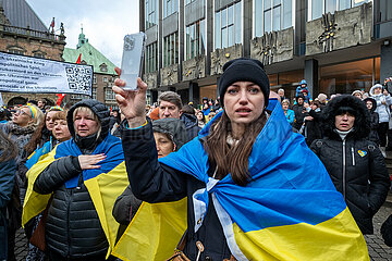 Deutschland  Bremen - Jahrestag des russischen Angriffkriegs gegen die Ukraine  ukrainische Fluechtlinge und Teilnehmer der Demonstration WE STAND WITH UKRAINE singen ihre Nationalhymne