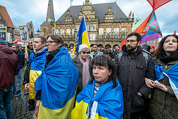 Deutschland  Bremen - Jahrestag des russischen Angriffkriegs gegen die Ukraine  ukrainische Teilnehmer der Demonstration WE STAND WITH UKRAINE (hinten das Rathaus)