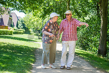 Rentnerehepaar macht einen Spaziergang in der Sommerhitze