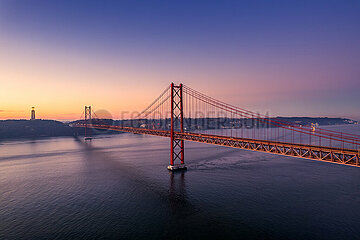 Portugal. Lisbon. Aerial view of the April 25 Bridge at sunrise with Christ the King in the background. It is the first suspension bridge over the Tagus