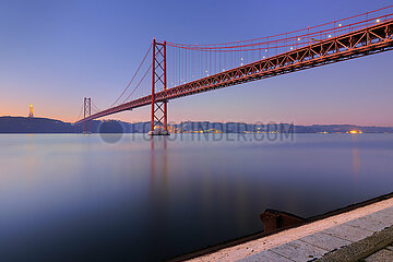 Portugal. Lisbon. Aerial view of the April 25 Bridge at sunrise with Christ the King in the background. It is the first suspension bridge over the Tagus
