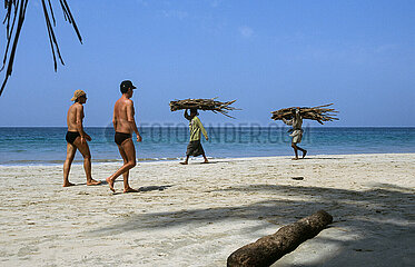 Thandwe  Myanmar  Touristen und Einheimische  die Brennholz tragen gehen am Strand von Ngapali Beach entlang