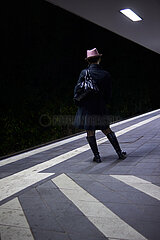 Eine Frau steht auf einem Bahnsteig und wartet.