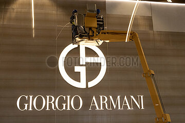 Doha  Katar  Bauarbeiter auf einer Hebebuehne vor dem Logo und Schriftzug von Giorgio Armani