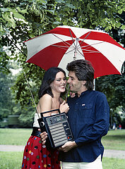 Berlin  Deutsche Demokratische Republik  junges Paar hoert unter ihrem Regenschirm Musik aus einem Kofferradio