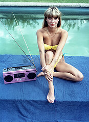 Berlin  Deutsche Demokratische Republik  junge Frau im Bikini sitzt an einem Swimmingpool und hoert Musik aus einem Kassettenrecorder