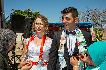 Tuerkei  Bogazkoey Sariyahsi - Polnisch-tuerkisches Brautpaar bei traditioneller Hochzeit auf dem Dorf in Anatolien  das Paar wird nach einem Brauch mit Geldscheinen dekoriert