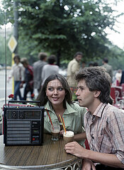 Berlin  Deutsche Demokratische Republik  junges Paar hoert in einem Cafe Musik aus einem Kofferradio