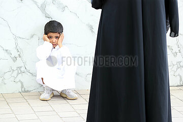 Doha  Katar  kleiner Junge sitzt traurig vor seiner Mutter am Boden