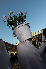 Doha  Katar  Mann traegt einen Blumenkuebel mit weissen Rosen auf dem Kopf