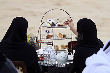 Doha  Katar  arabische Frauen essen auf einer Veranstaltung suesses Gebaeck von einer Etagere