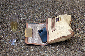 Ascot  Grossbritannien  Kunststoffglas mit Sekt und Handtasche mit Mobiltelefon auf dem Boden