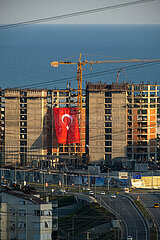 Tuerkei  Antalya - Baustelle eines Hochhauses mit riesiger tuerkischer Flagge an der Fadssade  hinten das Mittelmeer
