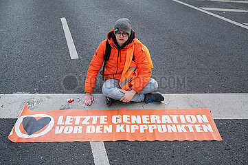 Berlin  Deutschland  Klimademonstrant der Letzten Generation hat sich auf der Fahrbahn festgeklebt und blockiert eine Strasse