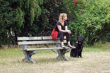 Dranse  Deutschland  Frau sitzt neben ihrem Hund auf der Lehne einer Parkbank