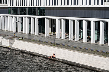 Berlin  Deutschland  Mann sonnt sich in der Fruehlingssonne am Ufer der Spree am Humboldthafen