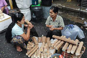 Yangon  Myanmar  Eine Frau kauft auf einem Strassenmarkt Thanaka-Holz um daraus Paste fuer Kosmetik zu machen