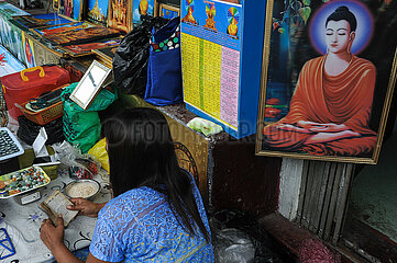 Yangon  Myanmar  Eine Frau liest an ihrem Strassenstand in einem Buch