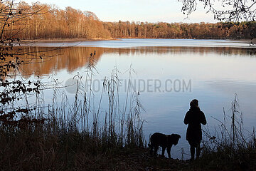 Warnow  Deutschland  Silhouette: Frau steht neben ihrem Hund am Ufer eines Sees