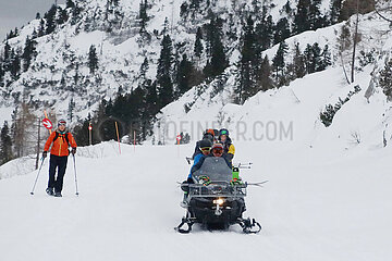 Krippenbrunn  Oesterreich  Menschen fahren auf einem Schneemobil eine Skipiste hinunter