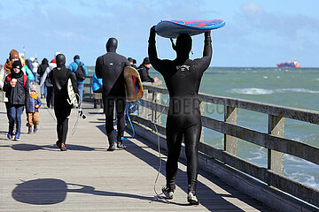 Binz  Deutschland  Surfer laufen auf der Seebruecke zum Meer