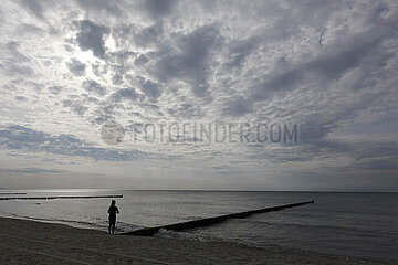 Wustrow  Deutschland  Silhouette: Frau steht bei bedecktem Himmel am Strand