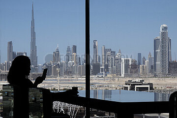 Dubai  Vereinigte Arabische Emirate  Silhouette: Frau sitzt an einem Fenster mit Blick auf die Stadt und den Burj Khalifa