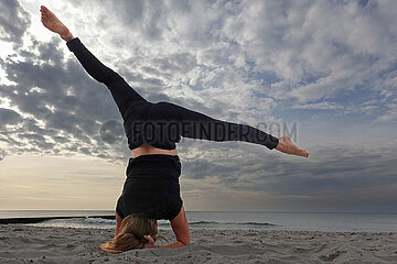 Wustrow  Deutschland  Frau macht am Strand beim Yoga einen Kopfstand