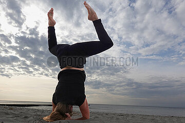 Wustrow  Deutschland  Frau macht am Strand beim Yoga einen Kopfstand