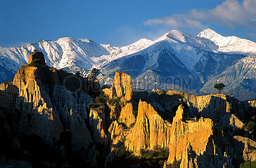 FRANCE. PYRENEES-ORIENTALES (66) CONFLENT REGION. THE FAIRY CHIMNEYS OF THE ORGANS OF ILLE-SUR-TET WITH THE SNOW-CAPPED CANIGOU IN THE BACKGROUND. A HOODOO IS A MODEL OF EROSION WHICH TAKES THE FORM OF A COLUMN OF SOFT ROCK SURMOUNTED BY A MORE RESISTANT CAP.