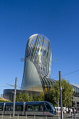 FRANCE. GIRONDE (33). BORDEAUX. THE TRAM IN FRONT OF THE CITE DU VIN: IT IS A CULTURAL AND TOURIST CENTER DEDICATED TO WINE. ITS SHAPE EVOKES A GNARLED VINE STOCK (ARCHITECTURE: XTU AGENCY. ANOUK LEGENDRE AND NICOLAS DESMAZIERES)