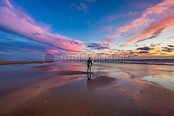 FRANCE. GIRONDE (33) ARCACHON BASIN. A SURFER ON THE BEACH FACING THE SUNSET
