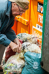 armer Rentner sucht in einem Müll nach verwertbaren Gegenständen