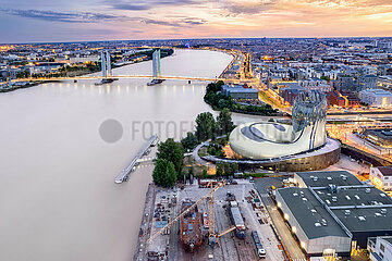 FRANCE. AQUITAINE. GIRONDE (33) BORDEAUX. AERIAL VIEW OF THE CITE DU VIN  THE GARONNE RIVER AND THE ENTRANCE TO THE BASINS AFLOAT  AT SUNSET  WITH THE CHABAN DELMAS BRIDGE IN THE BACKGROUND