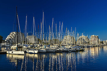 FRANCE. HERAULT (34) LA GRANDE-MOTTE. SAILBOATS IN THE HARBOR IN FRONT OF THE PYRAMID BUILDINGS
