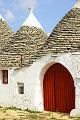 ITALY. PUGLIA. ALBEROBELLO. TRULLO  TYPICAL STONE HOUSE  WITH A RED DOOR IN THE ITRIA VALLEY.