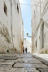 ITALY. PUGLIA. OSTUNI. TOURISTS WALKING IN A COBLESTONE STREET OF THE VILLAGE  ONE OF THE MOST BEAUTIFULL ITALIAN VILLAGES.