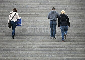 Drei Personen gehen eine Treppe hinauf