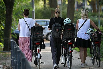 Drei Frauen mit Fahrraedern und Kindersitz