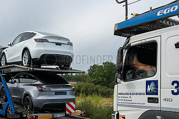 Deutschland  Gruenheide - Teslas auf Autotransporter vor der Tesla Gigafactory Berlin-Brandenburg  Beine eines pausierenden LKW-Fahrers aus der Slowakei