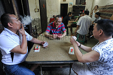Chongqing  China  Chinesische Maenner rauchen Zigaretten bei einem Kartenspiel in der Altsatdt Shibati